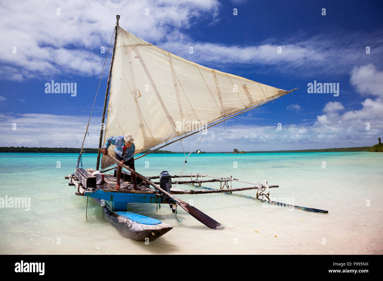Théodore, un 'local', kunie prépare une pirogue traditionnelle pour naviguer à travers la spectaculaire baie d'UPI sur l'île des Pins. Banque D'Images