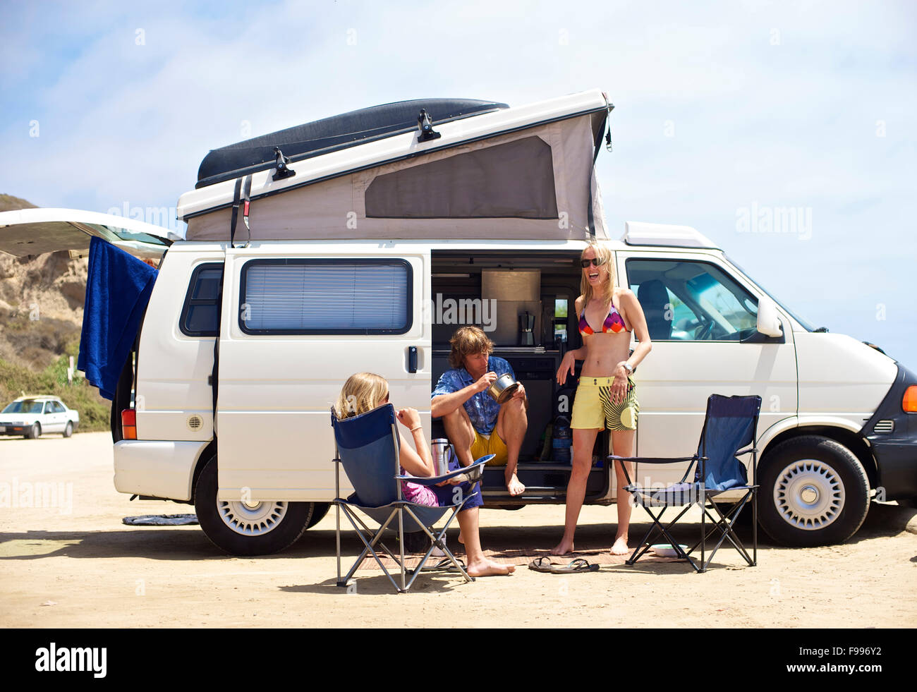 Trois personnes se tiennent à côté de leur van Camping Surf Beach, à San Onofre, Californie Banque D'Images