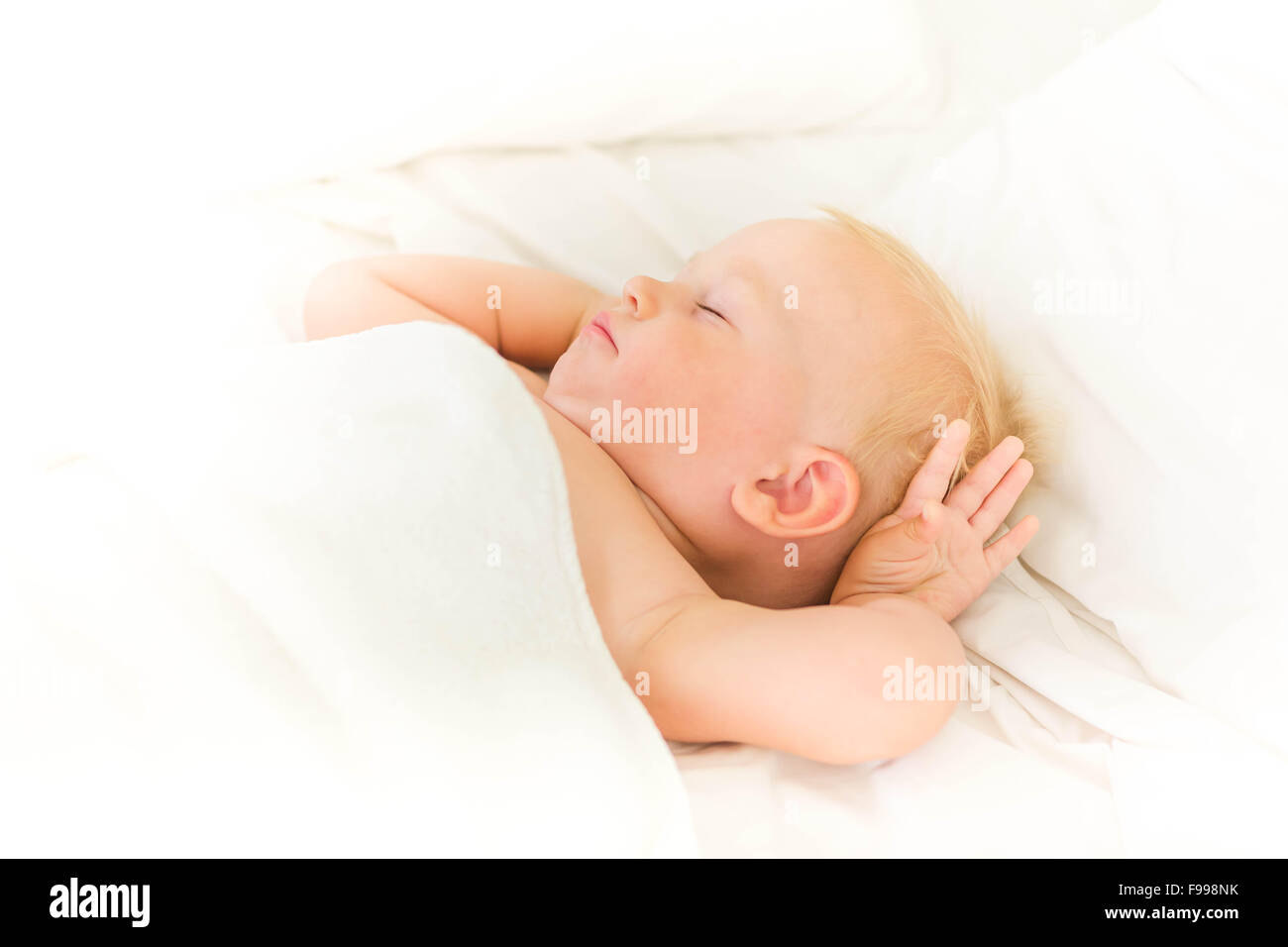 Bébé paisible sur un lit de dormir sur des draps blancs Banque D'Images
