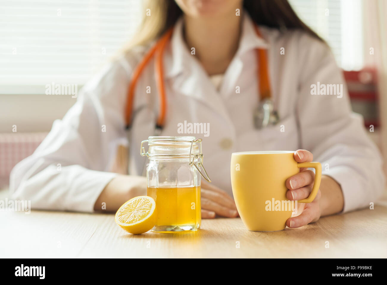 Détail de miel, citron et une tasse de thé avec médecin woman in background Banque D'Images