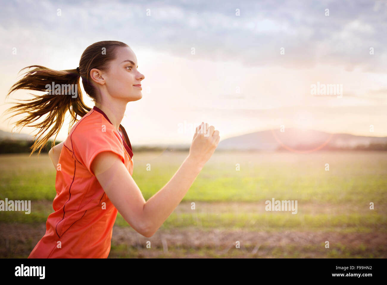 Cross-country trail running femme au coucher du soleil. Runnerwoman l'exercice à l'extérieur dans le cadre de vie sain. Banque D'Images