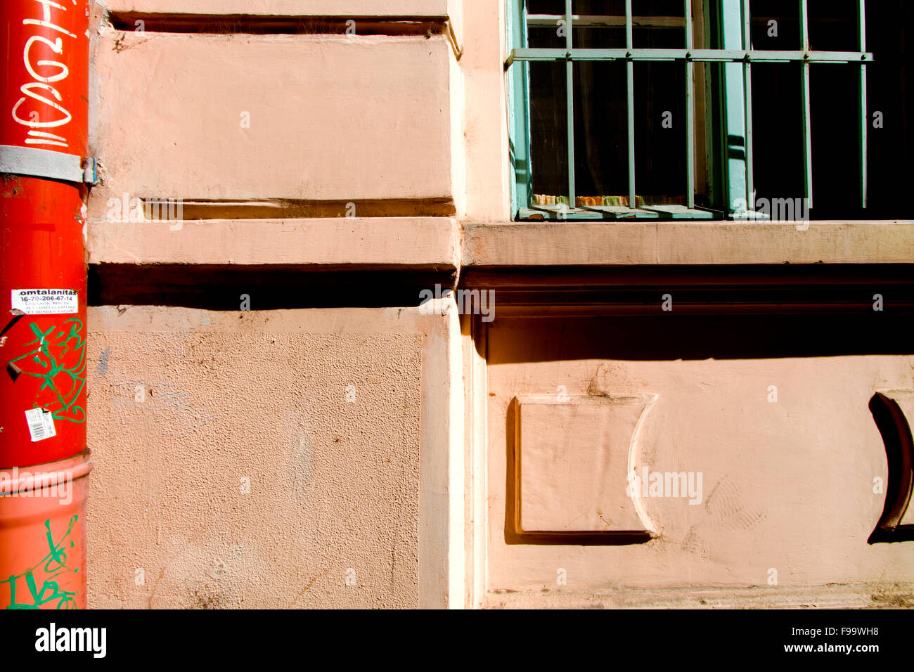 Sur un tuyau rouge vandalisées bâtiment orange vert avec une fenêtre grillée Banque D'Images