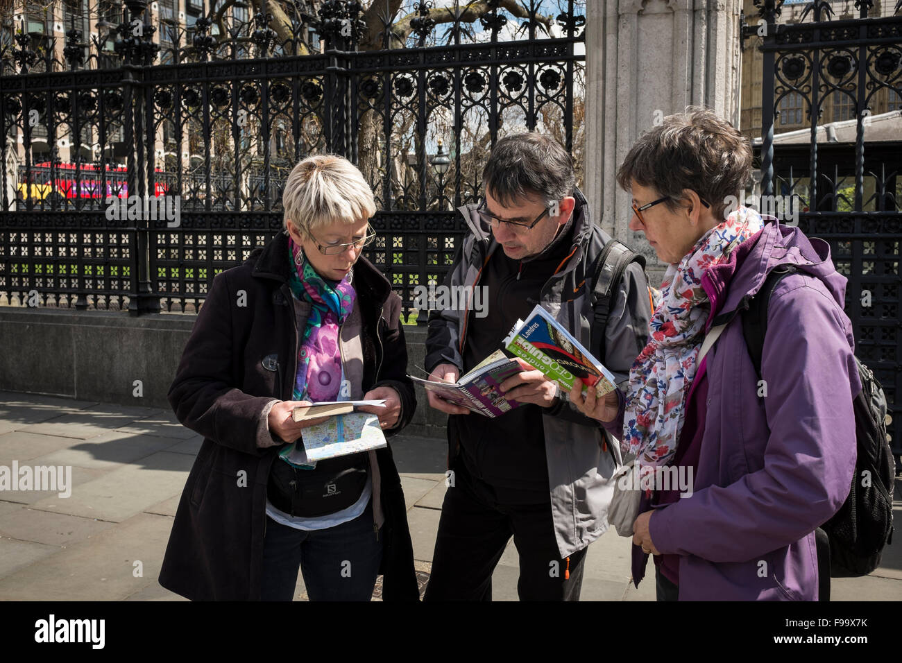 Trois touristes à la recherche et la vérification de la carte dans la rue de Londres, Royaume-Uni Banque D'Images