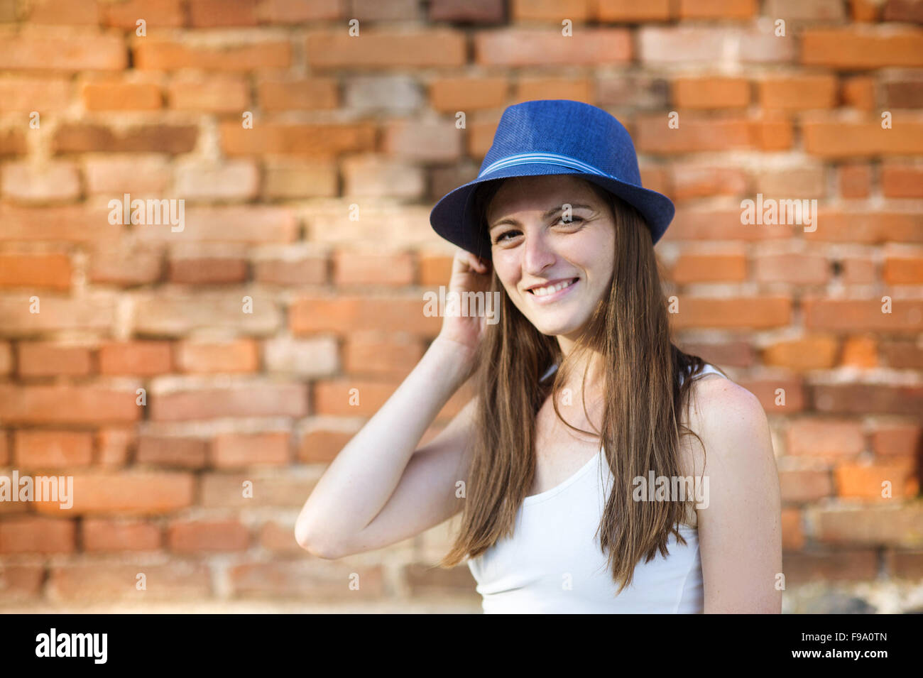 La femme en bleu hat standing par le mur de brique Banque D'Images