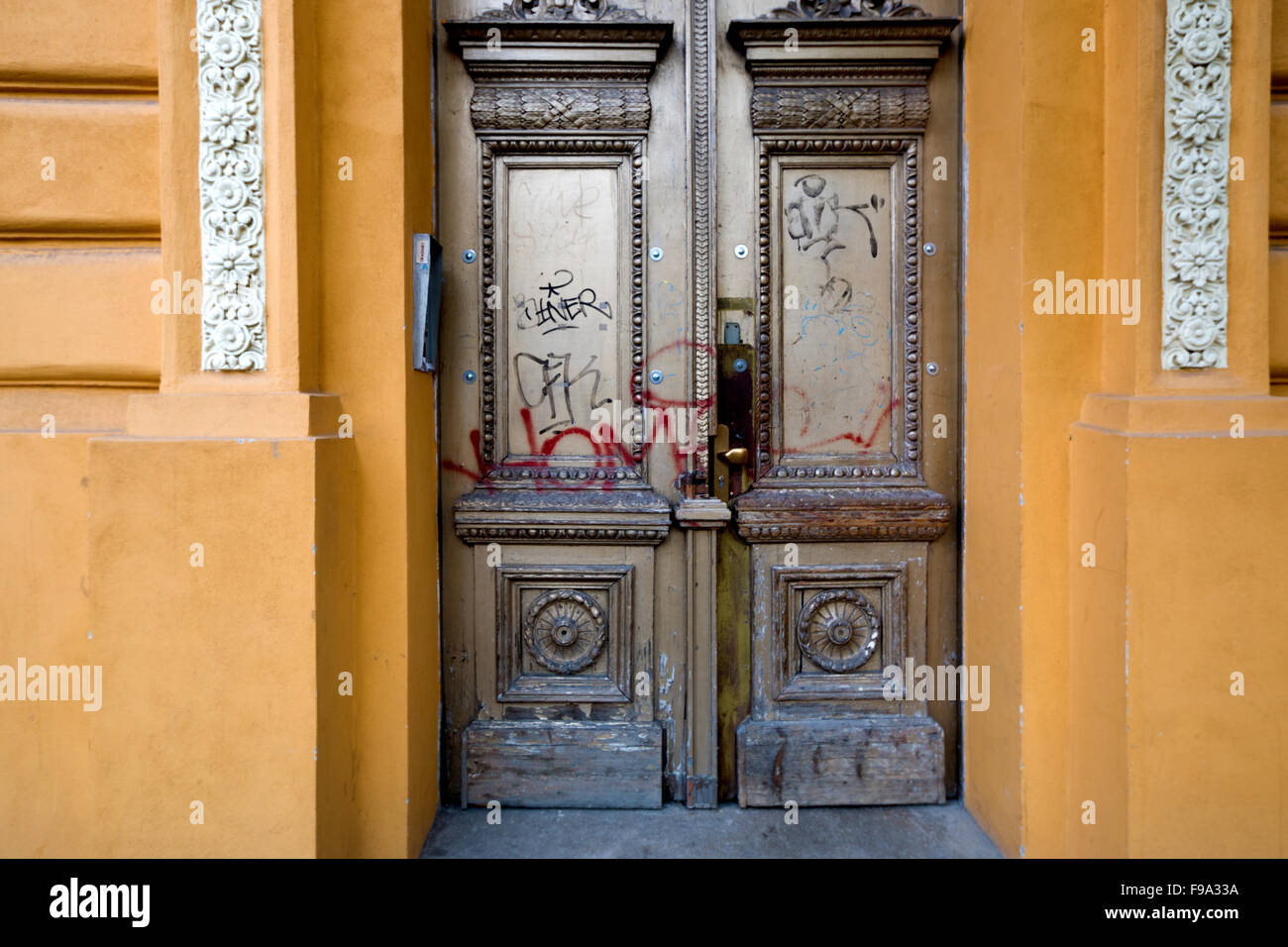 La porte d'or de graffitis sur un bâtiment jaune Banque D'Images