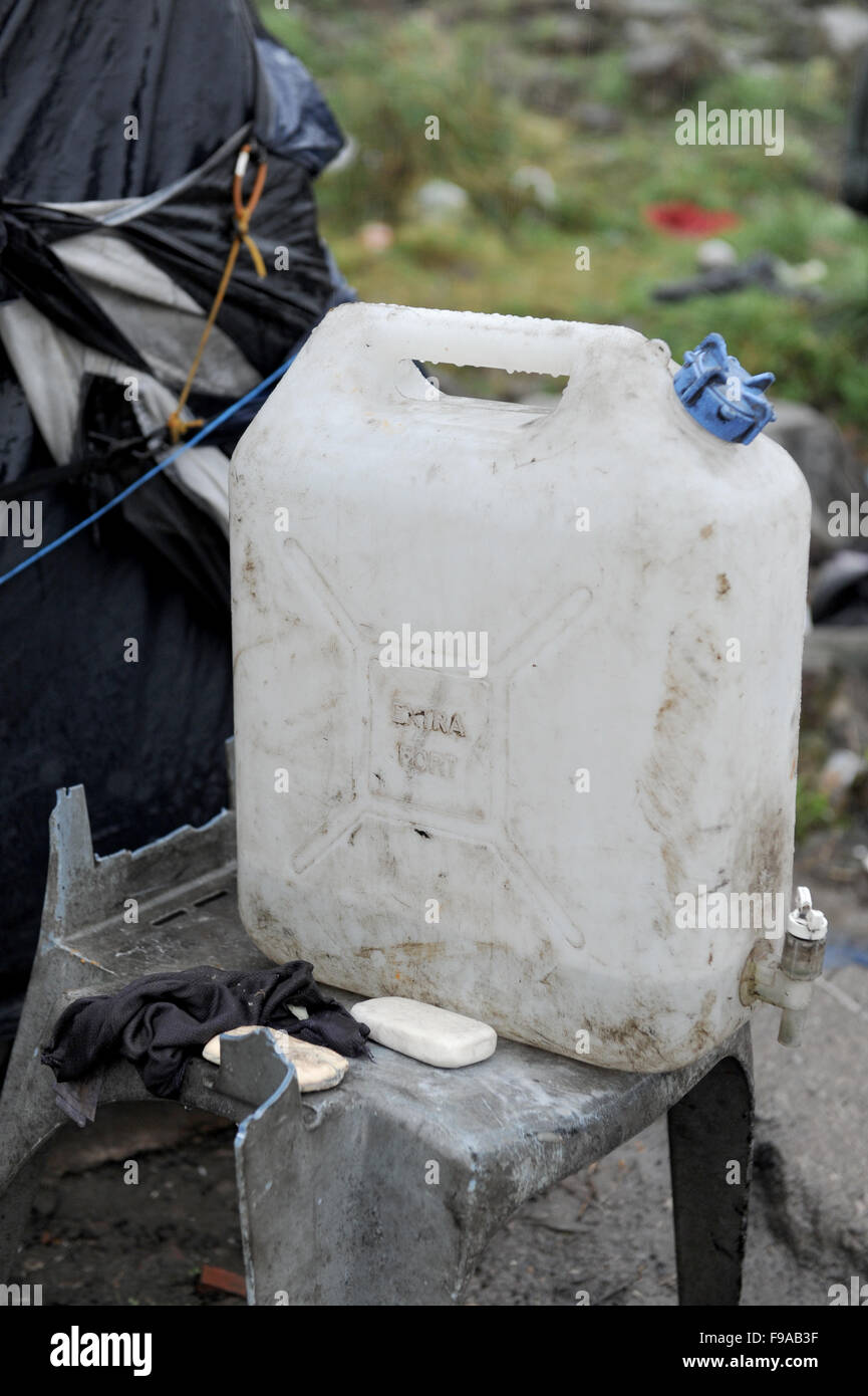 Jungle, Calais, France. Un seul récipient en plastique 3,78 l d'eau sale se dresse au milieu de la poubelle du camp. Un groupe de réfugiés utilisez cette pour recueillir de l'eau pour boire, se laver et cuisiner. Banque D'Images