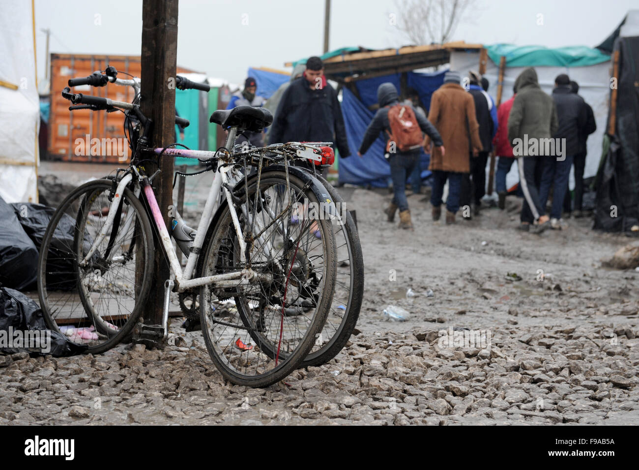 Jungle, Calais, France. Deux vélos enchaîné sur une des routes principales à travers le camp. Les réfugiés de leurs activités quotidiennes malgré le froid, nuageux et pluvieux. Banque D'Images
