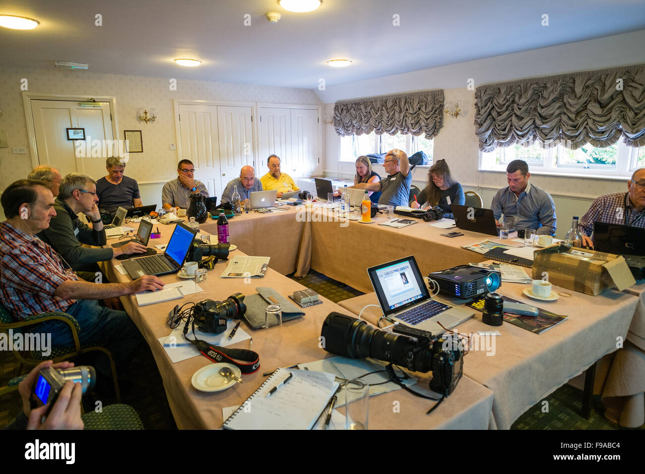 Un groupe de photographes assis autour d'une table et d'édition de photos numériques, leur traitement (faite dans le petit marché anglais ville de Cirencester) sur les ordinateurs portables dans une salle de réunion de l'hôtel lors d'un atelier d'une journée séminaire leçon classe tutoriel sur la photographie bibliothèque stock Alamy UK Banque D'Images