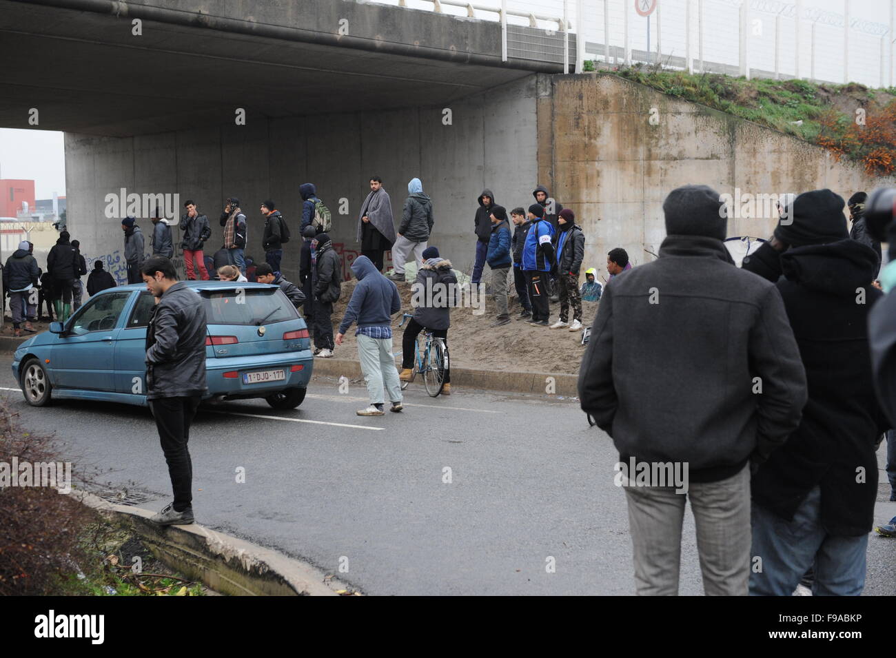 La Jungle, Calais, France. Les réfugiés et les migrants flâner par l'entrée du camp par l'autoroute gardé par des policiers Banque D'Images