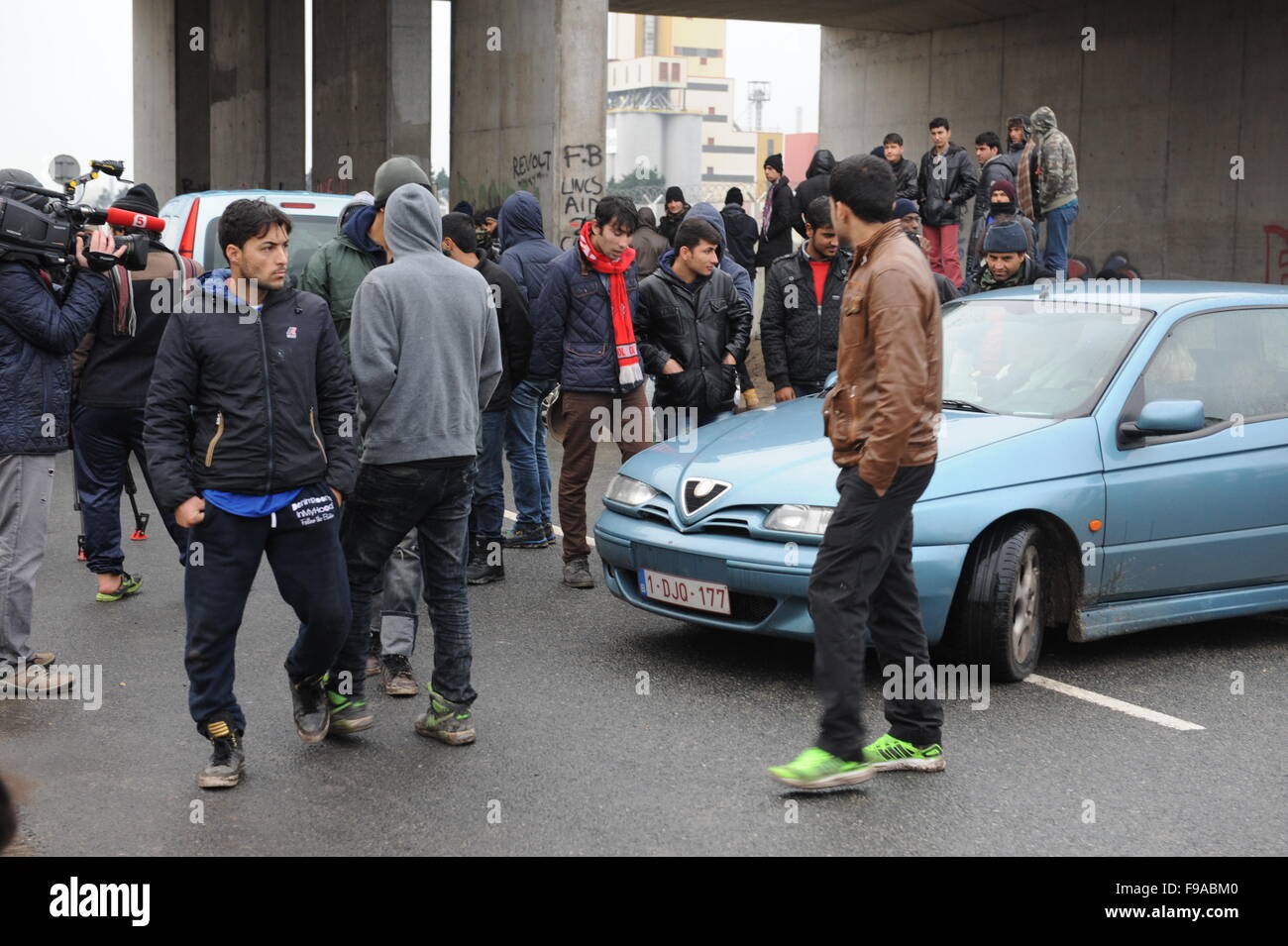 La Jungle, Calais, France. Les réfugiés et les migrants flâner par l'entrée du camp par l'autoroute gardé par des policiers Banque D'Images