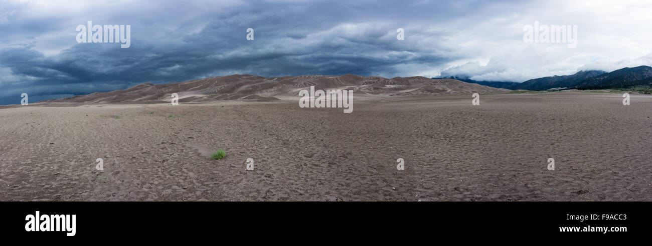 Un lit à sec s'étend avant de dunes de sable s'avancent jusqu'en face de montagnes du Colorado Banque D'Images