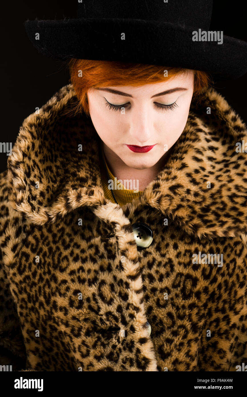 Un seul adolescent timide solo femme fille aux cheveux courts rouge flamme par elle-même, portant un manteau de fausse fourrure, regardant vers le bas, tête baissée , Royaume-Uni Banque D'Images