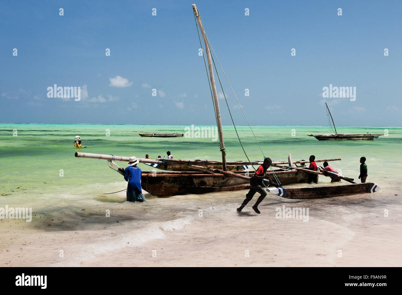 Les enfants regarder et jouer pendant la course de boutres annuel à Jambiani Zanzibar avec ciel bleu et de mer bleue et de sable blanc Banque D'Images