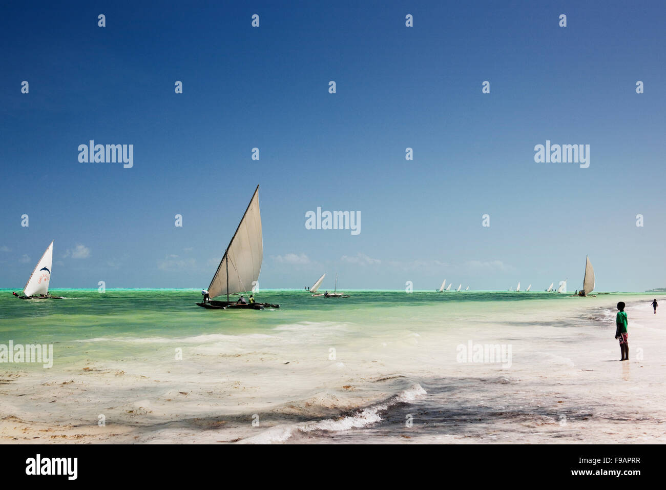 Un garçon regarde la course de boutres annuel à Jambiani Zanzibar avec ciel bleu et de mer bleue et de sable blanc Banque D'Images