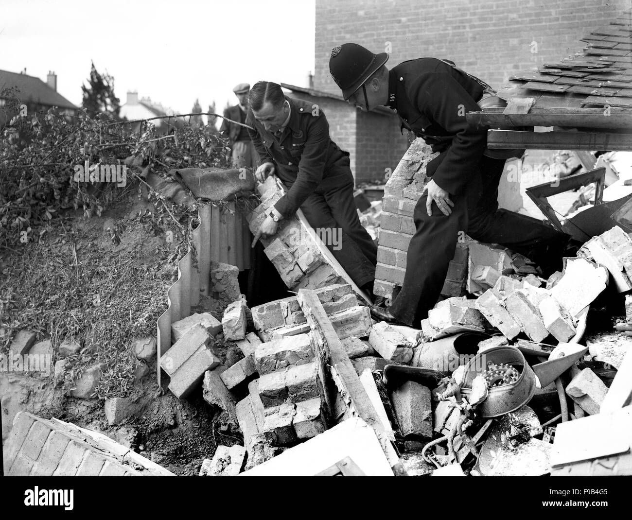 Un policier et de l'air directeur vérification des précautions Raid survivants dans un abri Anderson à Coventry blitz allemand suivants de la ville 1940 Banque D'Images