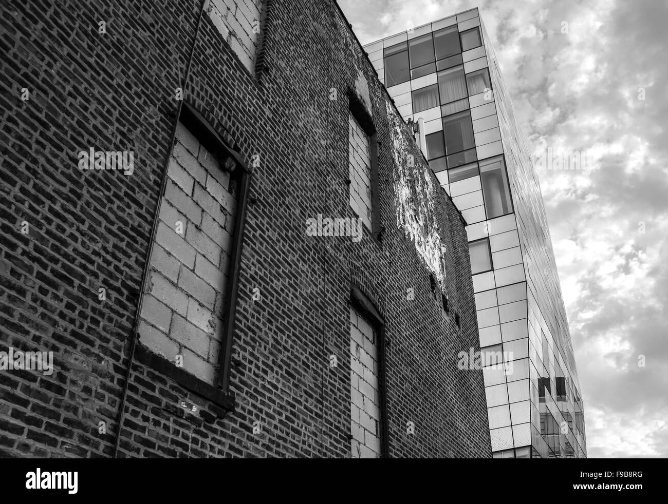 Un contraste d'un vieux bâtiment en brique avec une tour moderne en verre en monochrome. Tourné à New York. Banque D'Images