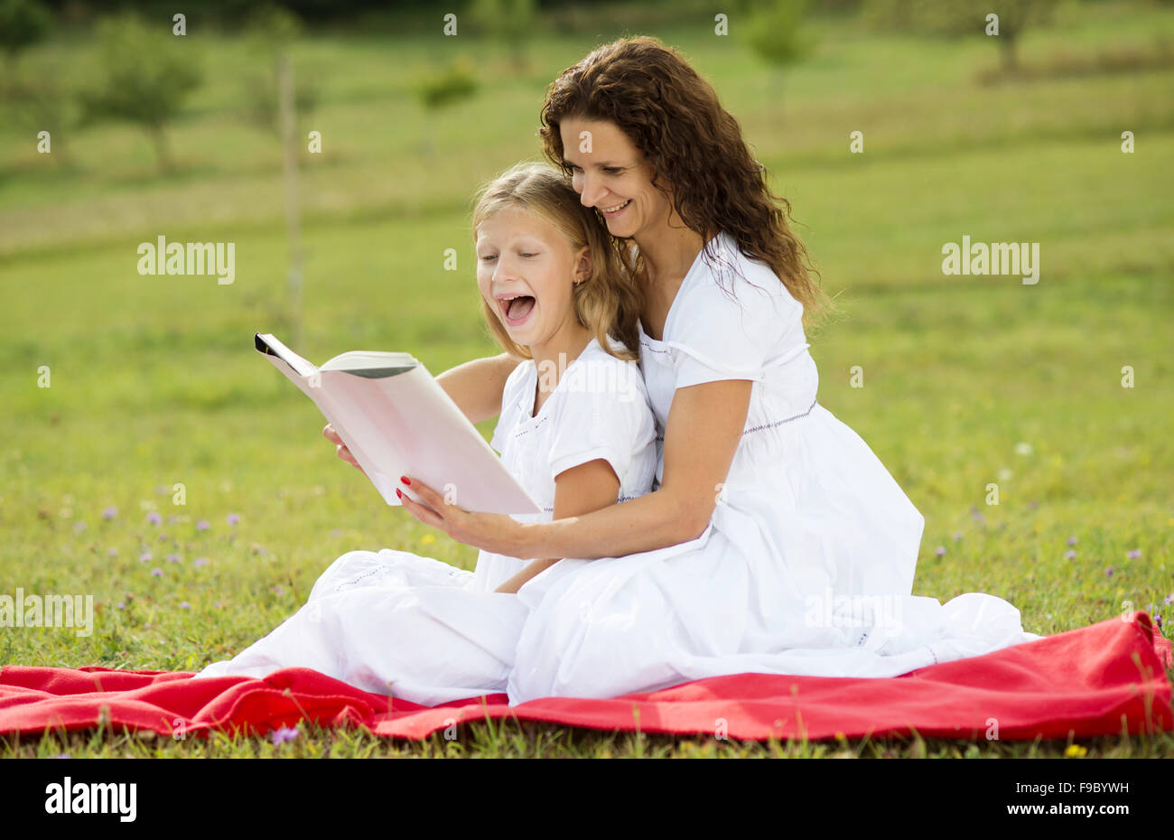 Mère est coin et lire un livre à ses enfants dans le vert du parc Banque D'Images
