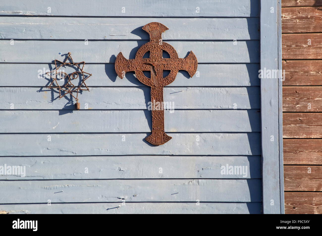 Un fil de soleil et du métal rouillé, une croix sur l'arrière-plan d'un parement en bois bleu pâle. Une bande de transition de brun d'évitement. Banque D'Images