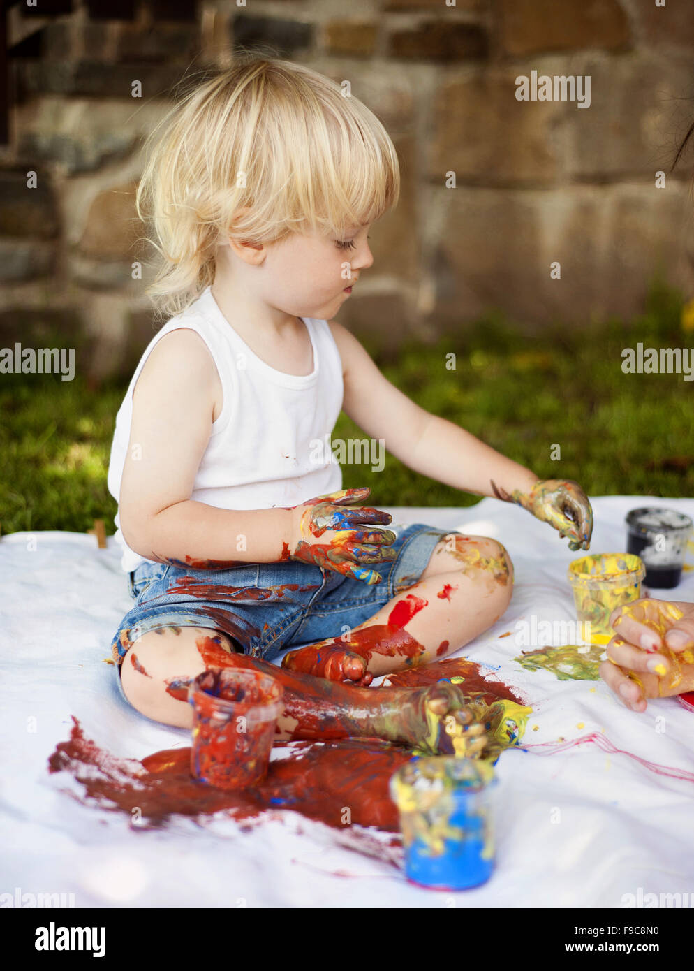 Peinture enfant mignon avec des couleurs vibrantes dans le jardin Banque D'Images