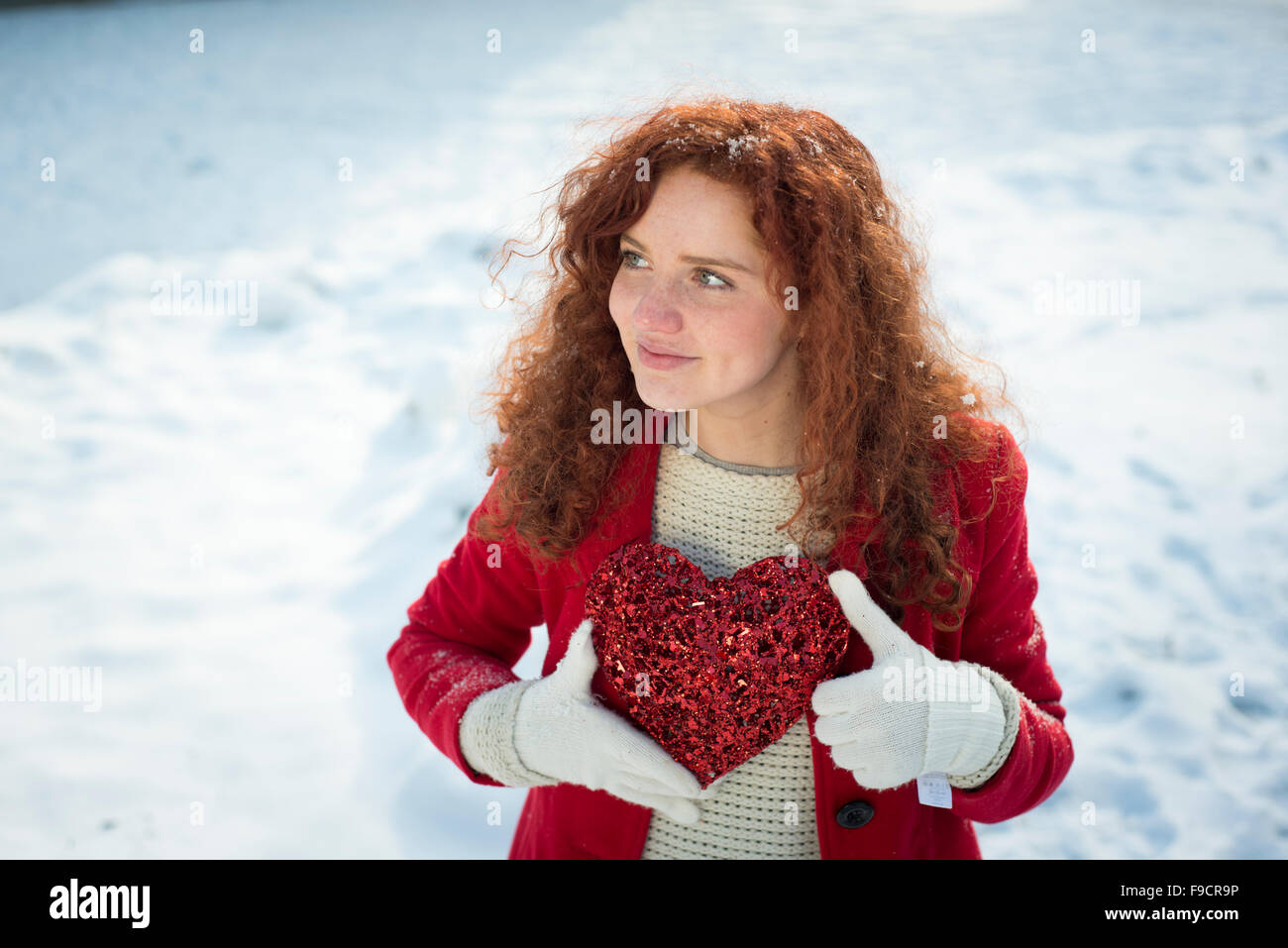 Lonely Girl in the red coat tient cœur et d'attente. Banque D'Images