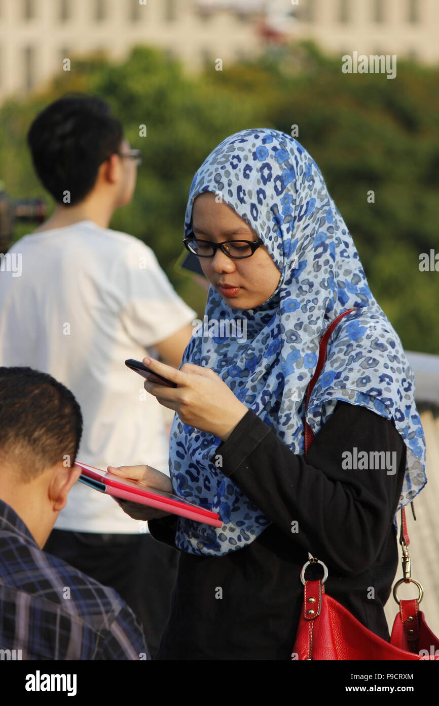 Fille de Malaisie moderne à l'aide de téléphone mobile et holding tablet computer Banque D'Images