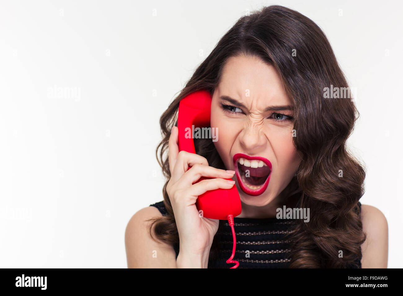 Close up of angry mad curly jeune femme style rétro en criant et en conversation sur téléphone sur fond blanc Banque D'Images