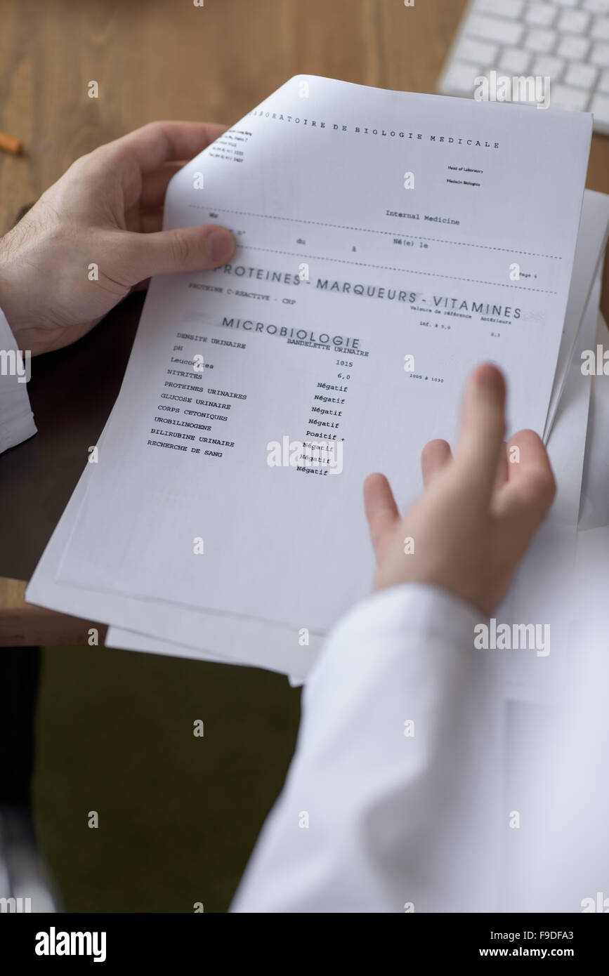 Un médecin travaillant avec les résultats du test de son patient at office Banque D'Images