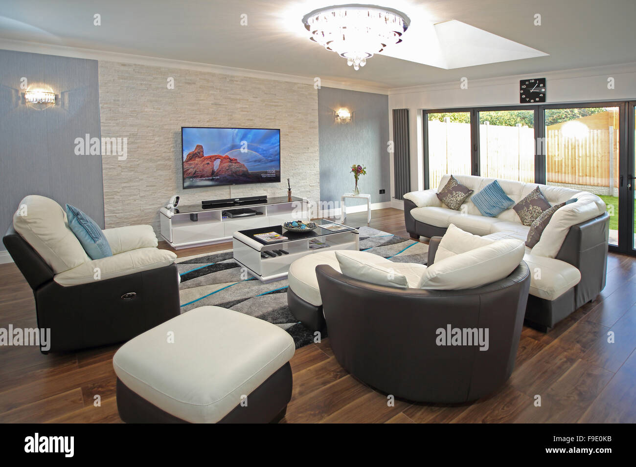 Le salon d'une maison récemment rénovée avec des canapés en cuir deux tons et grandes, une télévision murale à écran plat Banque D'Images