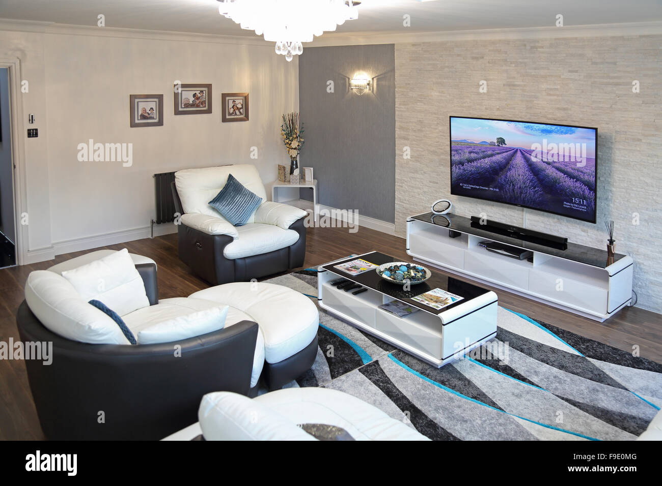 Le salon d'une maison récemment rénovée avec des canapés en cuir deux tons et grandes, une télévision murale à écran plat Banque D'Images