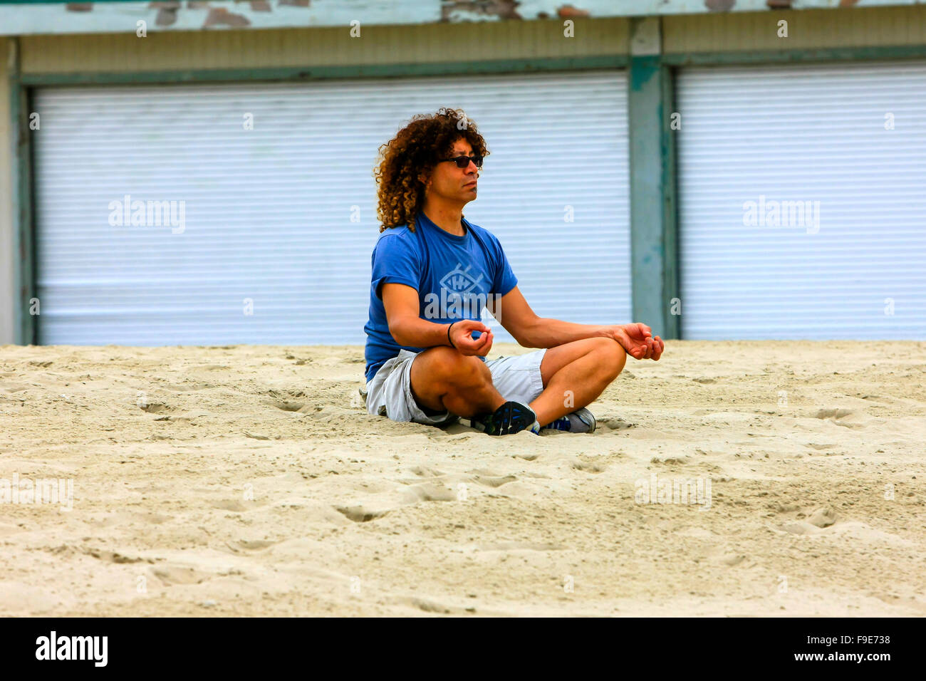 Un homme est assis et fait de son la méditation du matin sur la plage de Venice, Californie Banque D'Images