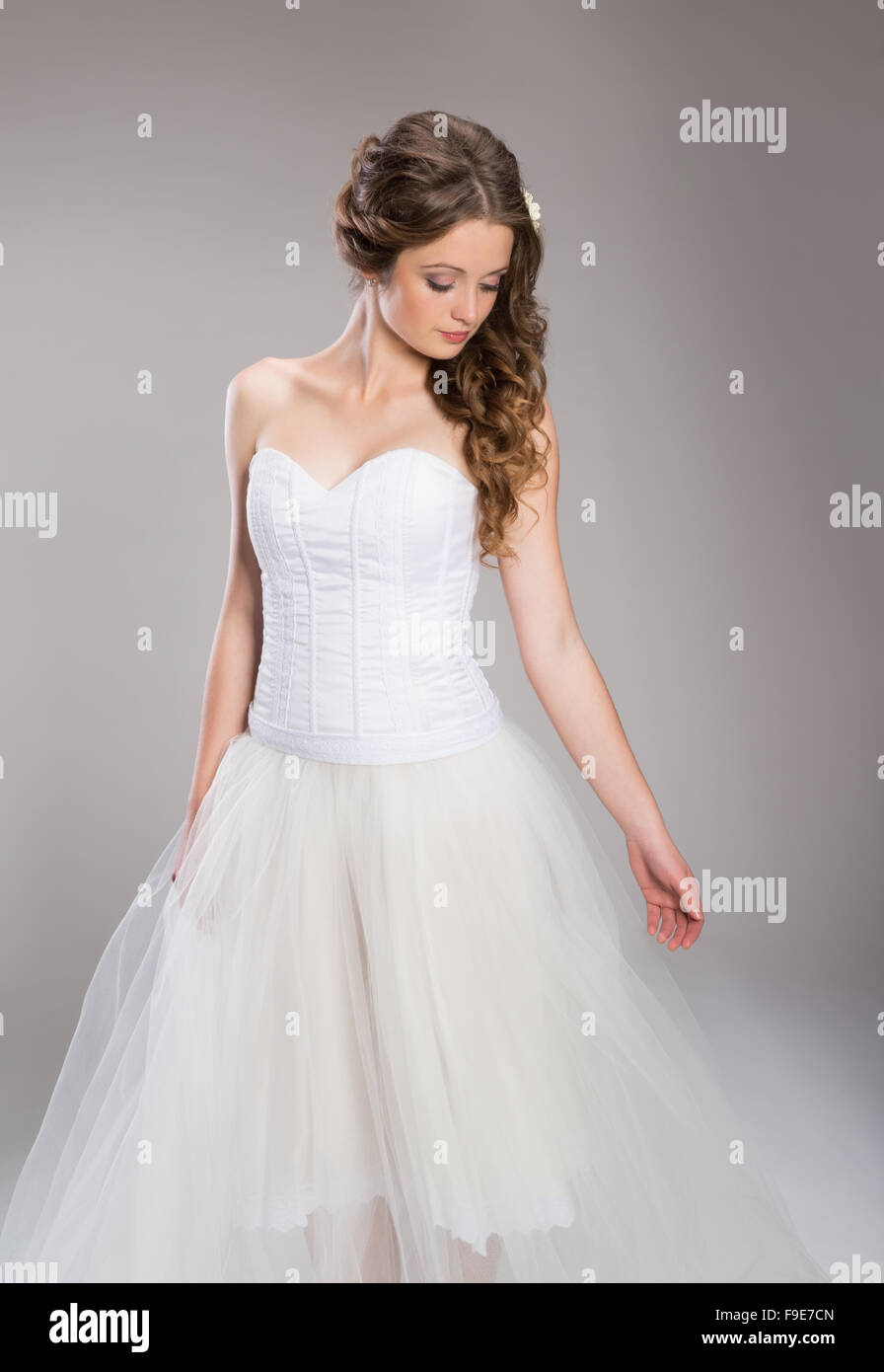 Vue latérale du young bride with hand on chin debout sur fond gris Banque D'Images