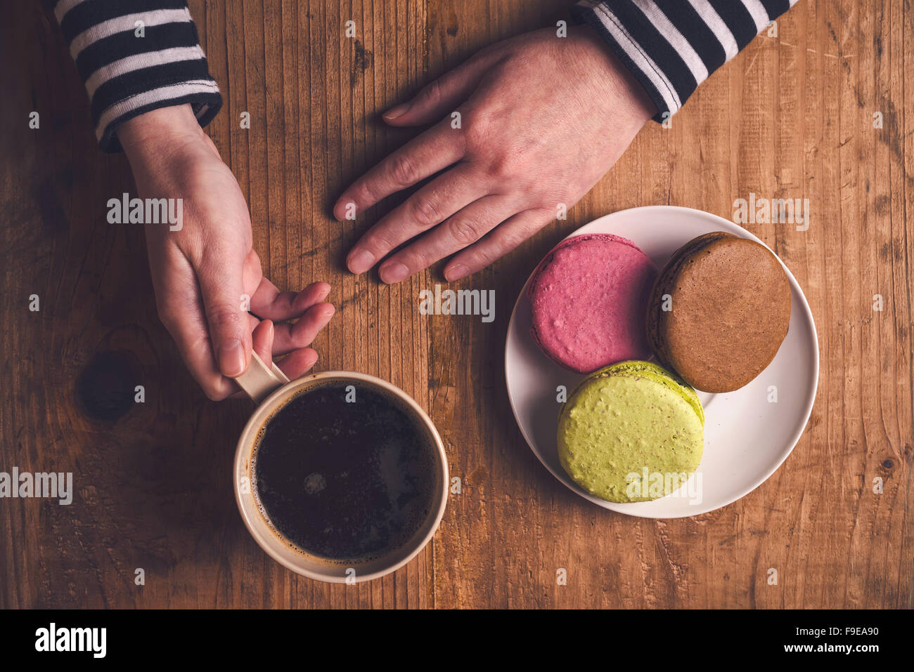 Café et biscuits macaron sur la table le matin, femme hand holding cup avec boisson chaude, vue d'en haut, aux couleurs rétro Banque D'Images