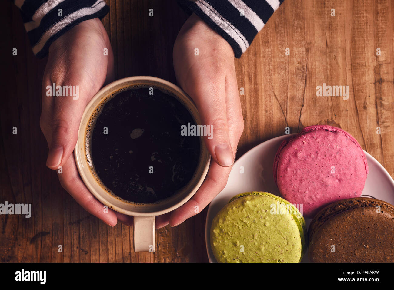 Café et biscuits macaron sur la table , femme hand holding cup avec boisson chaude, vue d'en haut, aux couleurs rétro Banque D'Images