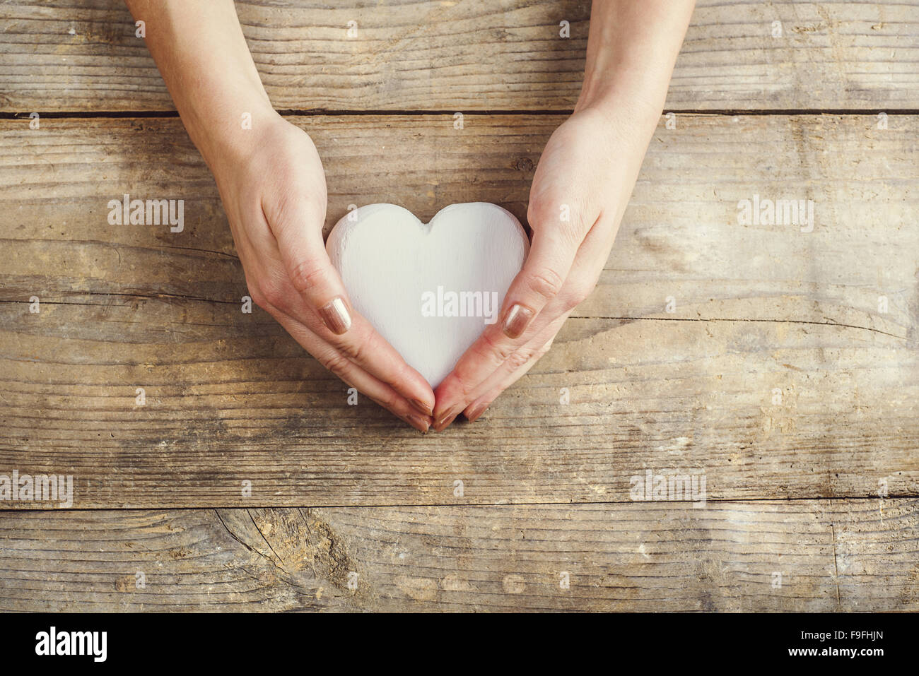 Les mains de l'homme et de la femme tenant un cœur ensemble. Studio shot sur un fond de bois, vue de dessus. Banque D'Images