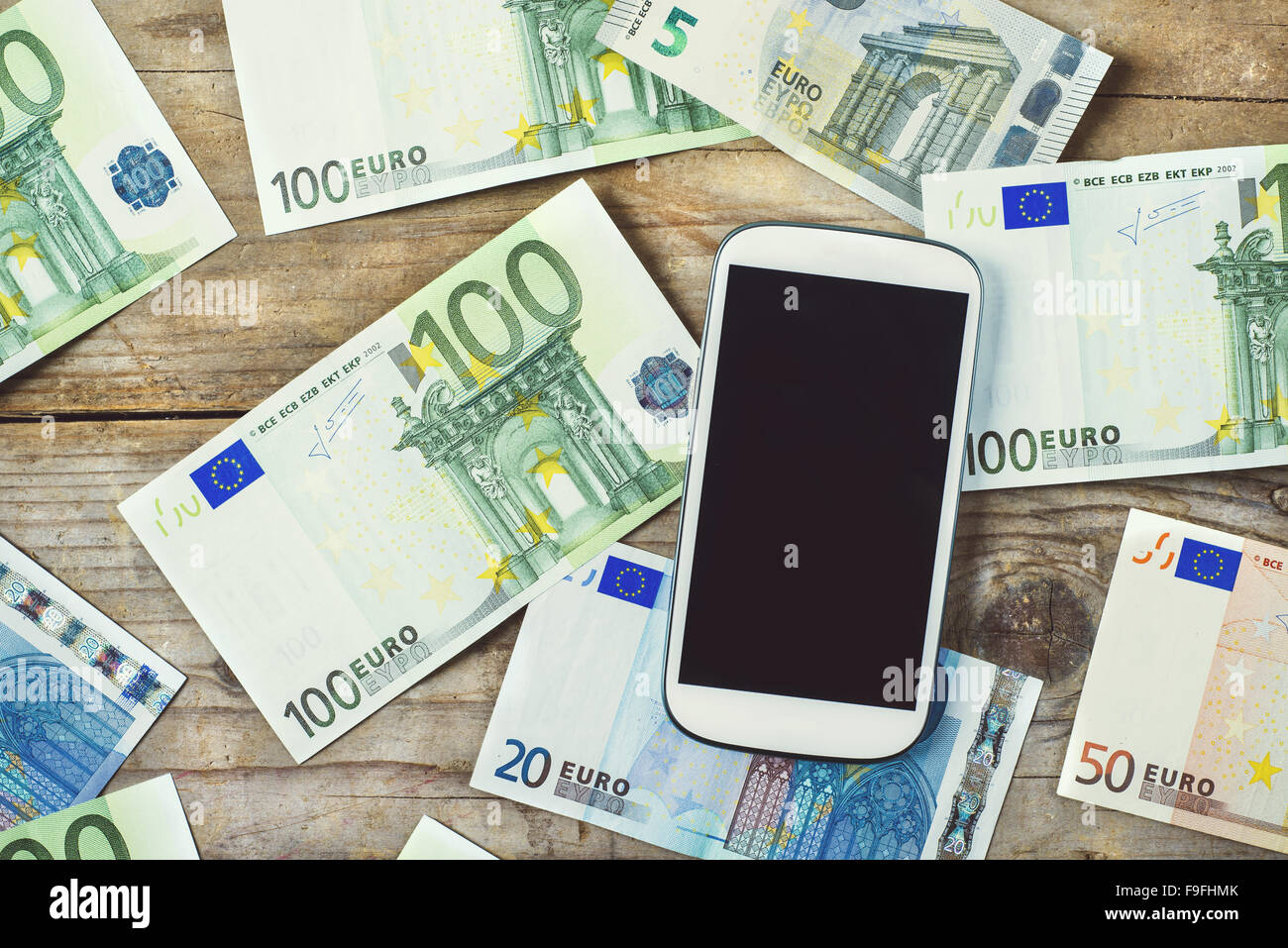 Smartphone et billets de la monnaie européenne éparpillés sur la table en bois. Vue de dessus. Banque D'Images