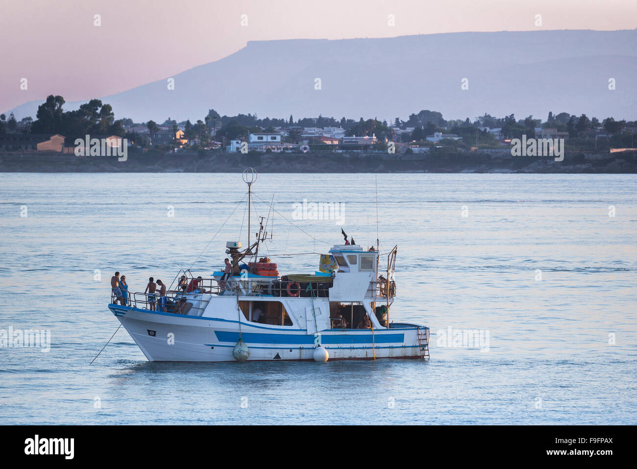 Bateau jeunes Méditerranée, vue au crépuscule des jeunes socialisant sur un grand bateau dans le port de Syracuse (Syracuse) Sicile, Italie Banque D'Images