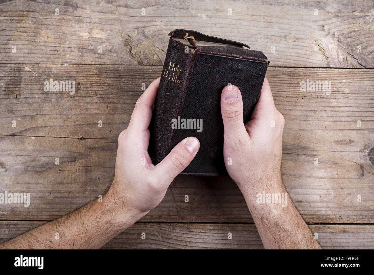 Hands holding Bible sur un bureau en bois. Banque D'Images