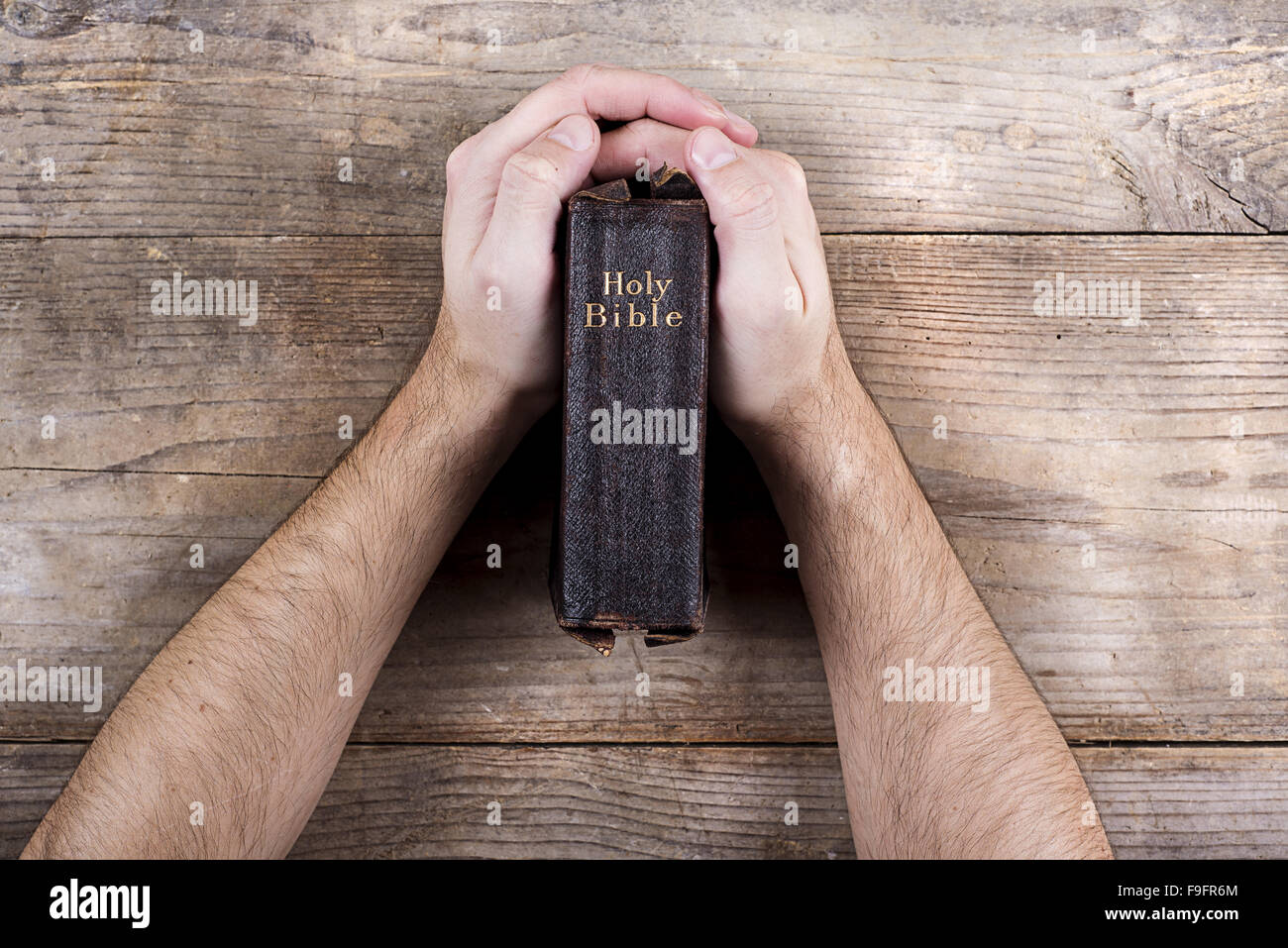 Hands holding Bible sur un bureau en bois. Banque D'Images