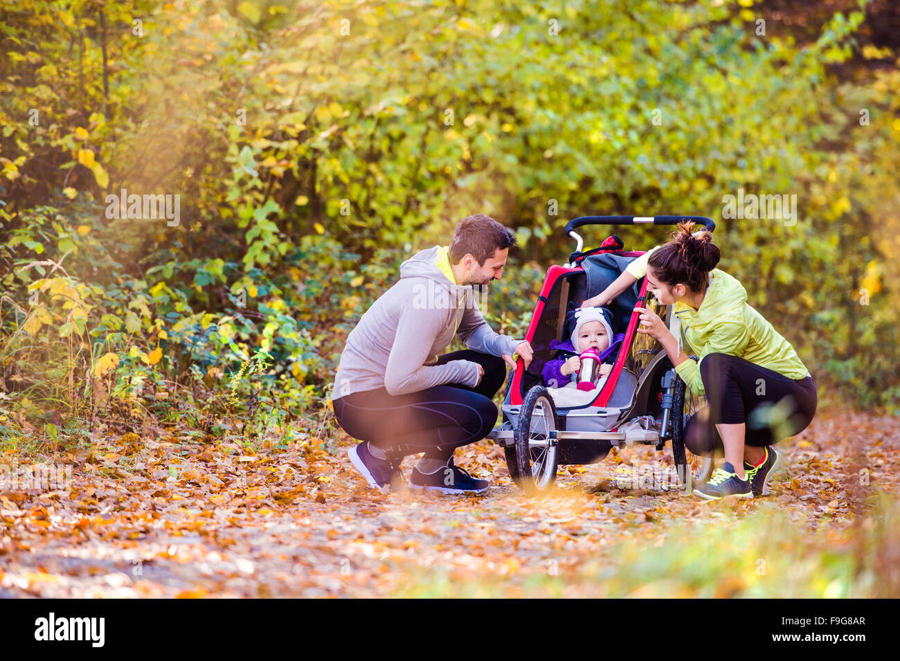 Beau jeune famille avec bébé en poussette fonctionne en dehors de la nature en automne Banque D'Images