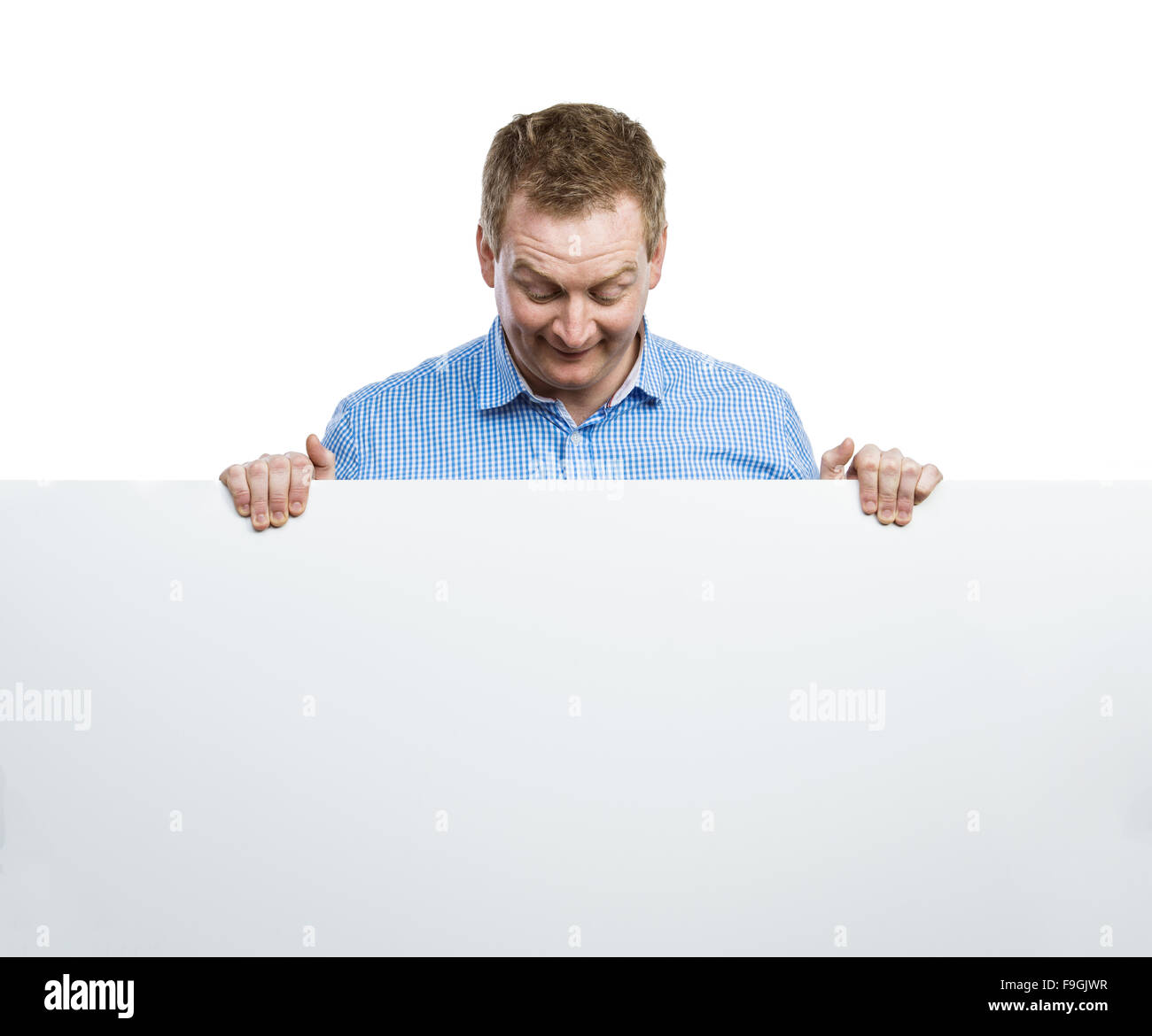 Jeune homme making funny face, holding a blank sign board. Studio shot sur fond blanc. Banque D'Images