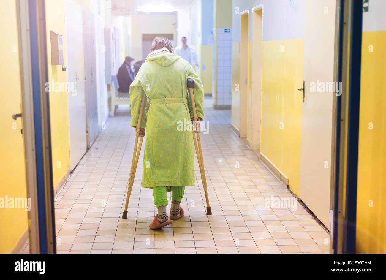 Senior woman blessés assis dans le couloir de l'hôpital holding béquilles Banque D'Images