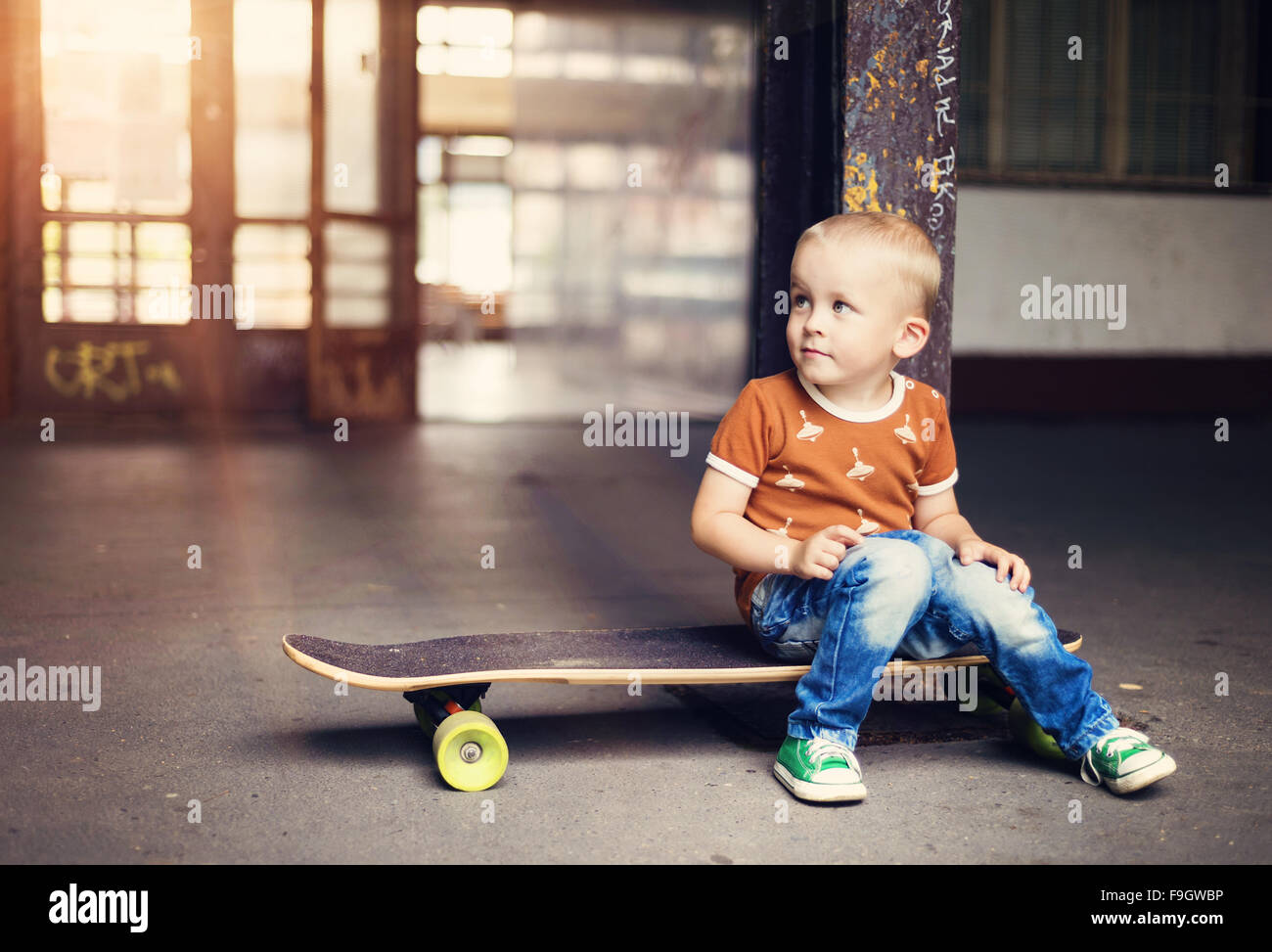 Adorable petit garçon avec son skateboard, lors d'une promenade en ville Banque D'Images