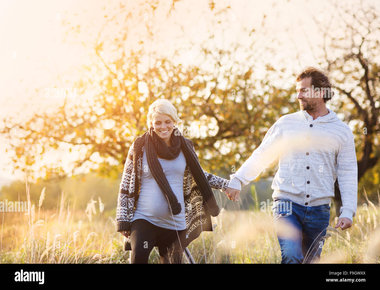 Happy young pregnant couple de passer du temps ensemble à l'extérieur dans la nature verte. Banque D'Images