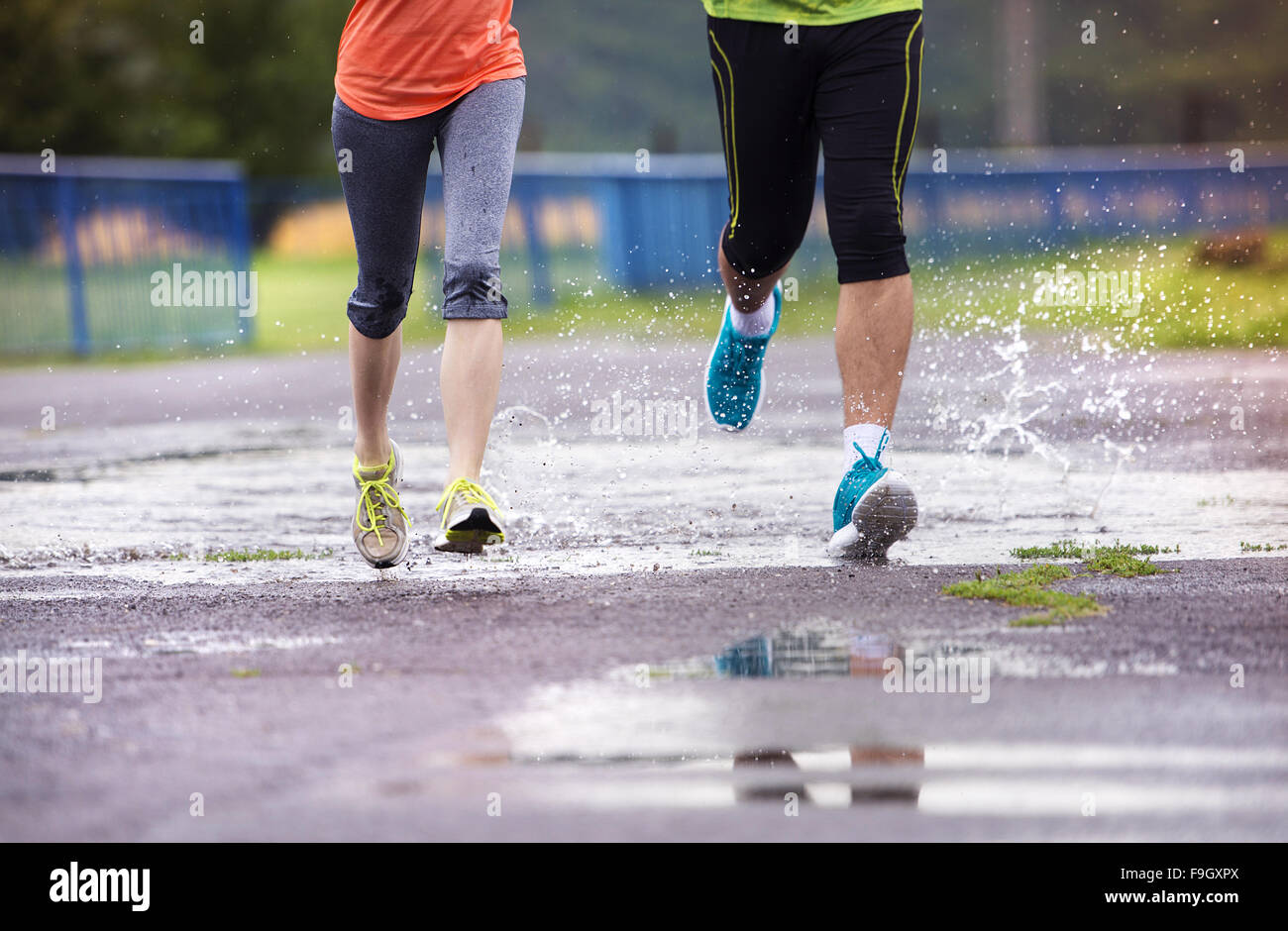 Jeune couple jogging sur l'asphalte par temps de pluie Banque D'Images