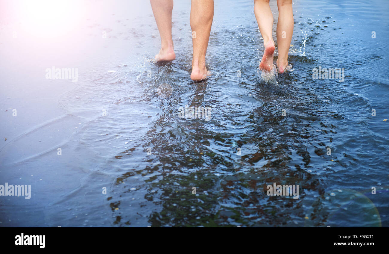 Méconnaissable la femme et l'homme marche pieds nus dans une flaque Banque D'Images