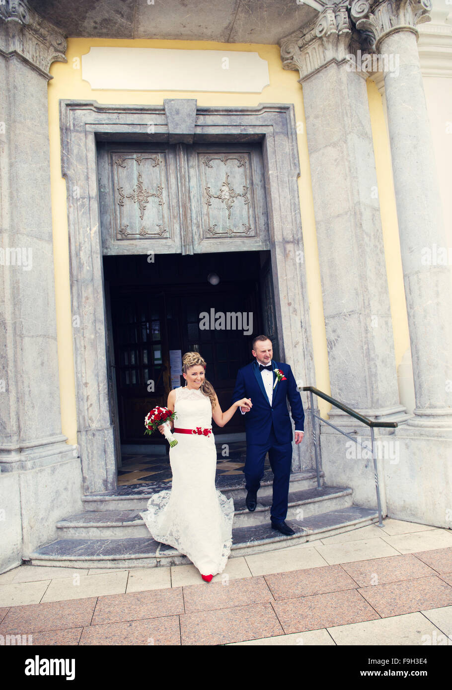 Mariée et le marié à la sortie de l'église main dans la main Banque D'Images
