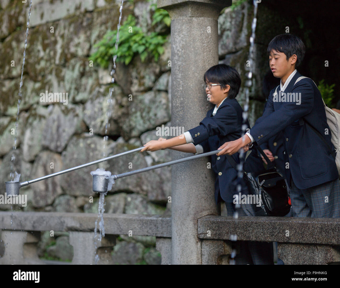 Les enfants attraper l'eau sainte pour les ablutions rituelles, le temple Kiyomizu-dera (c 8C AD) JAPON KYOTO Banque D'Images