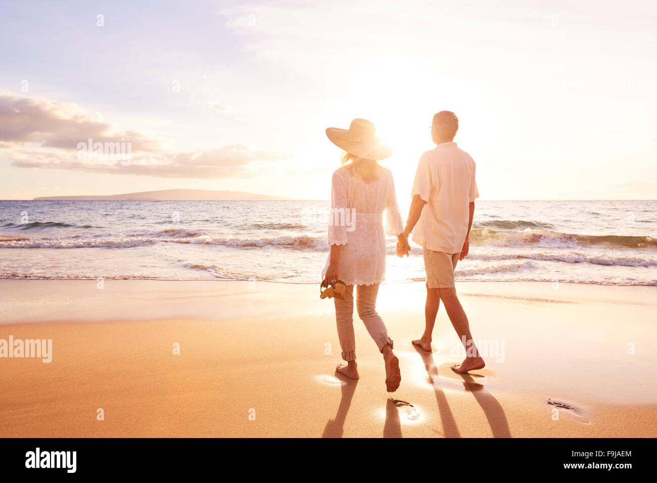 Happy Romantic Couple d'âge moyen avec sa promenade sur la plage au coucher du soleil. Voyage Vacances Concept de vie à la retraite Banque D'Images