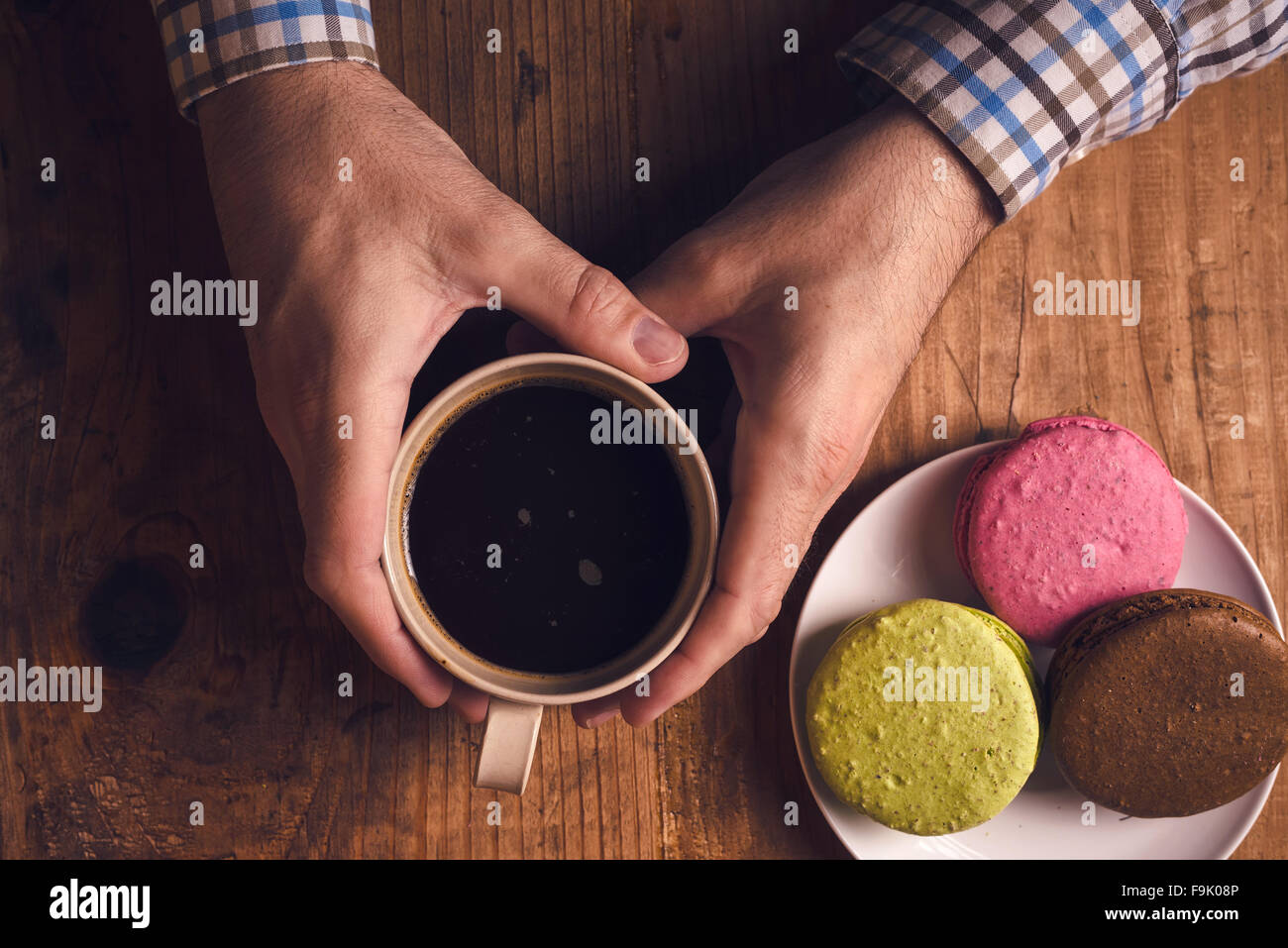 Café et biscuits macaron sur la table le matin, male hands holding cup avec boisson chaude, vue d'en haut, aux couleurs rétro Banque D'Images