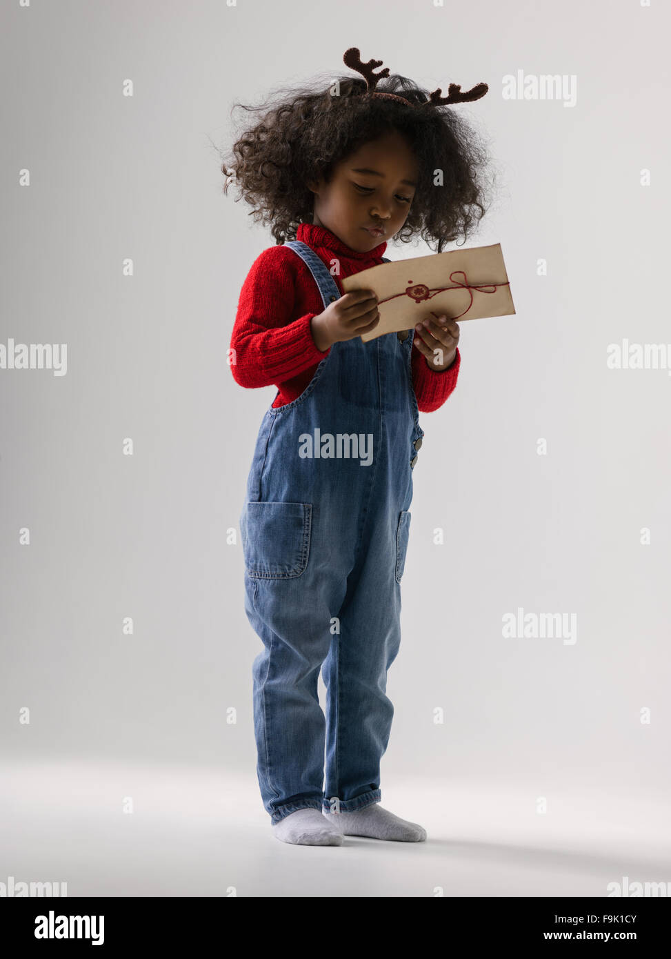Little girl holding africaine lettre du Père Noël portrait sur fond uni Banque D'Images